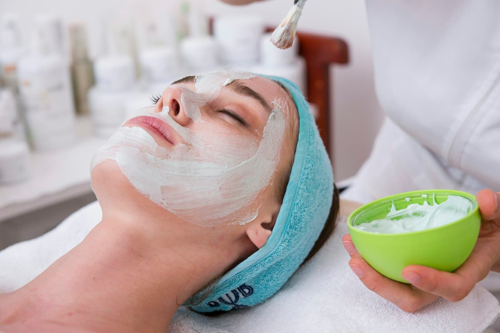 An aesthetician gently applying a nourishing mask during a facial