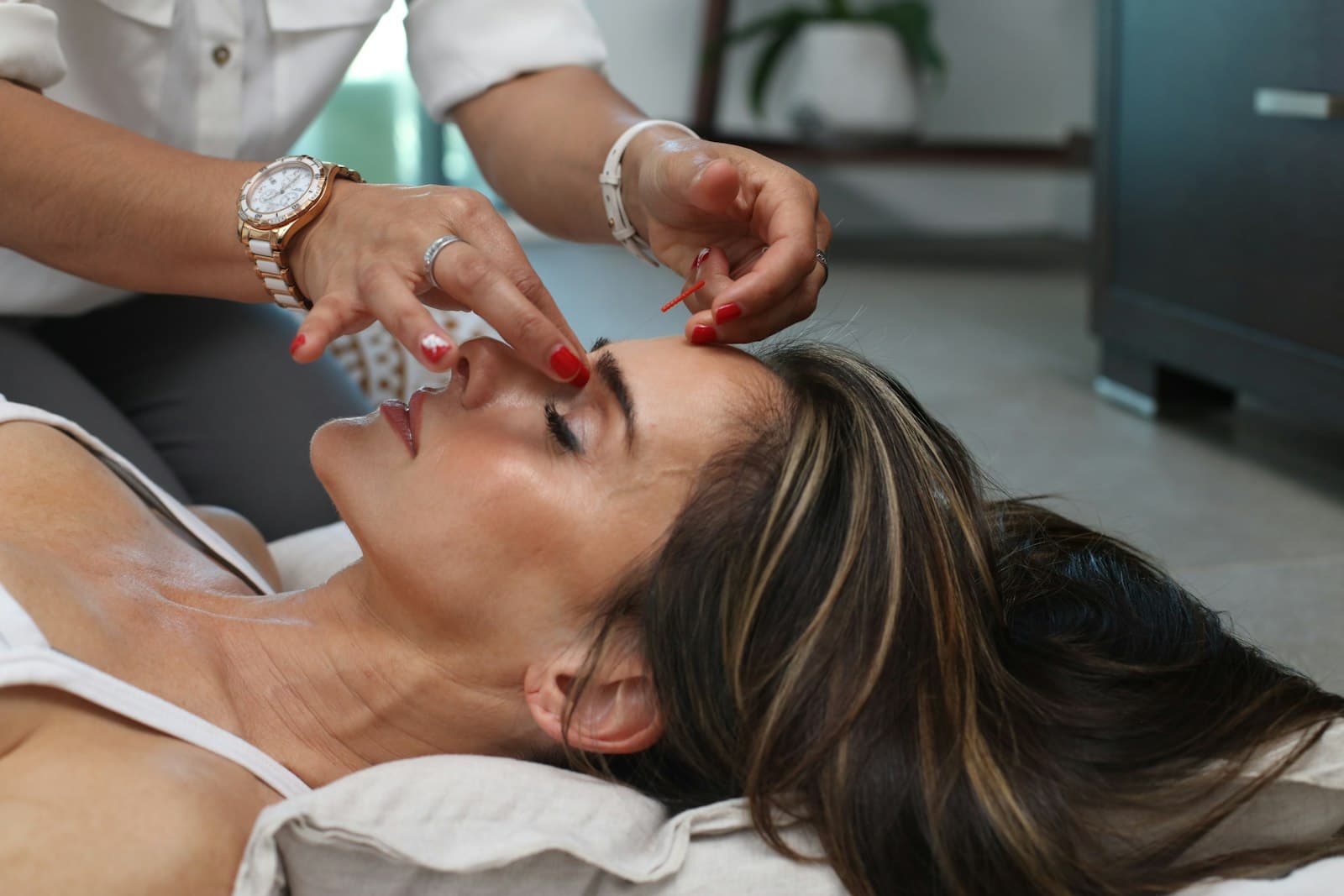 Aesthetician shaping a client's brows with precision tools