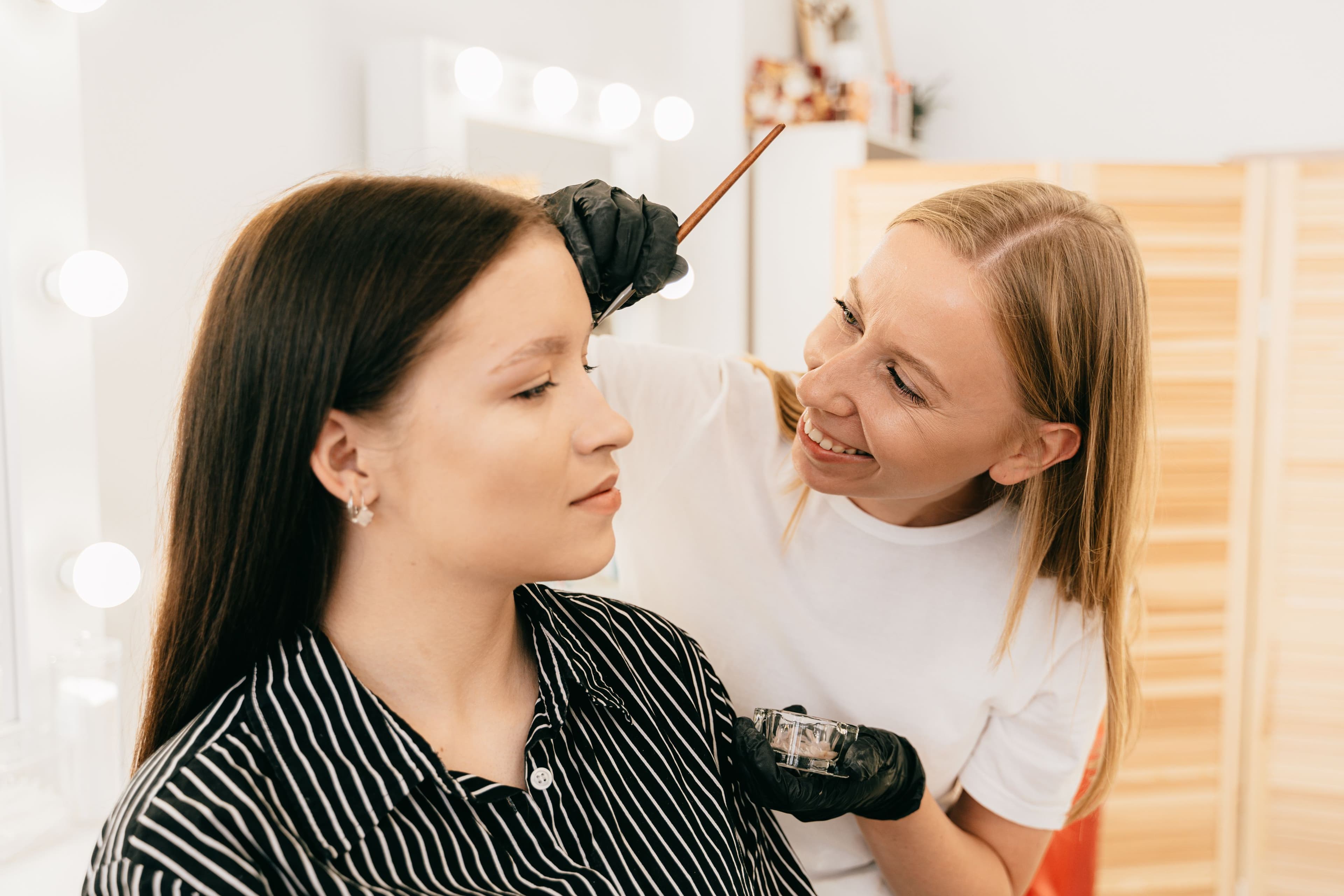 A stylist applying brow tint with a precision brush